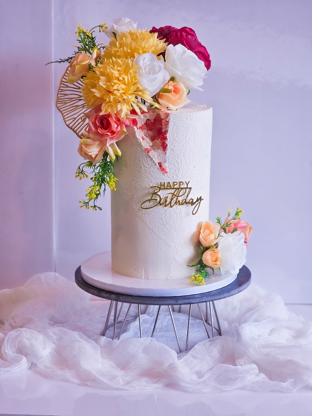 White birthday cake crowned with orange, yellow and pink florals