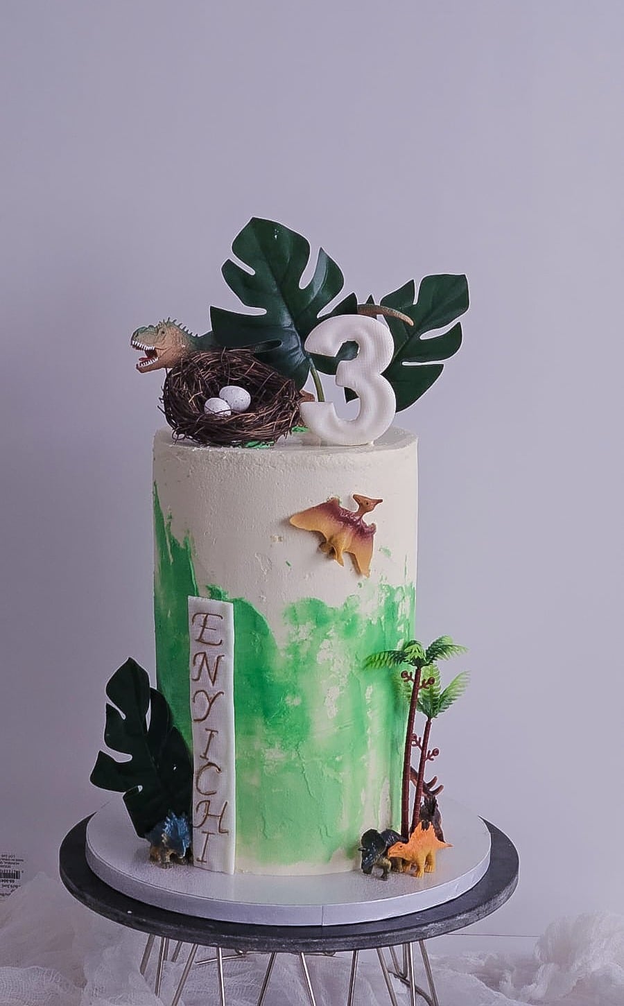 Green jungle-themed third birthday cake with palm leaves and animals
