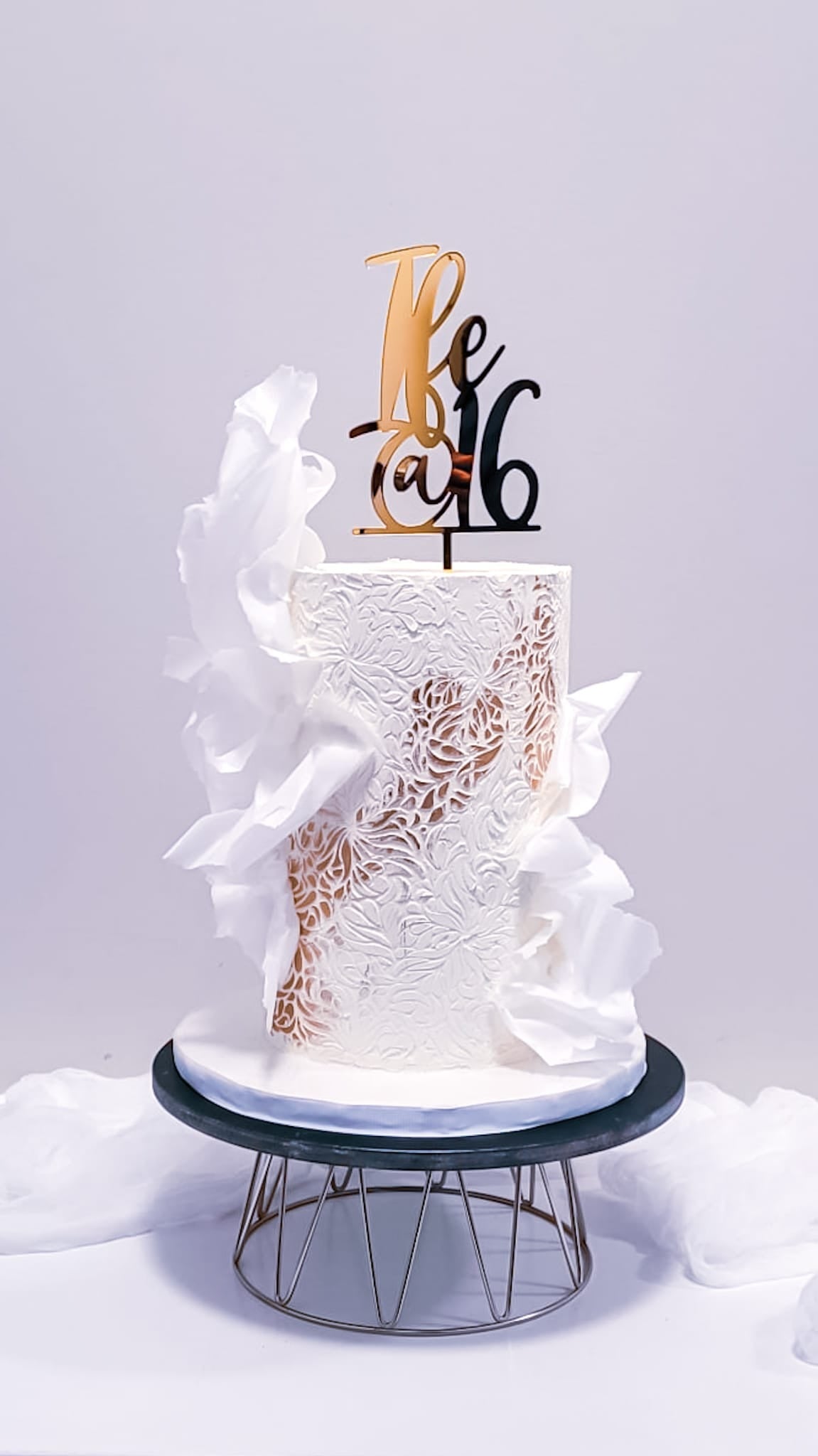 White sweet sixteen cake with wafer-paper sails and gold lace